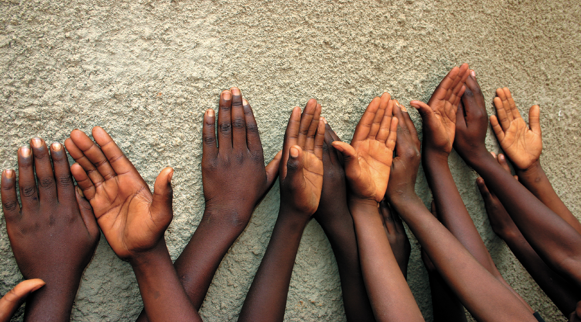 Overhead view of many young people reaching together in a circle.
